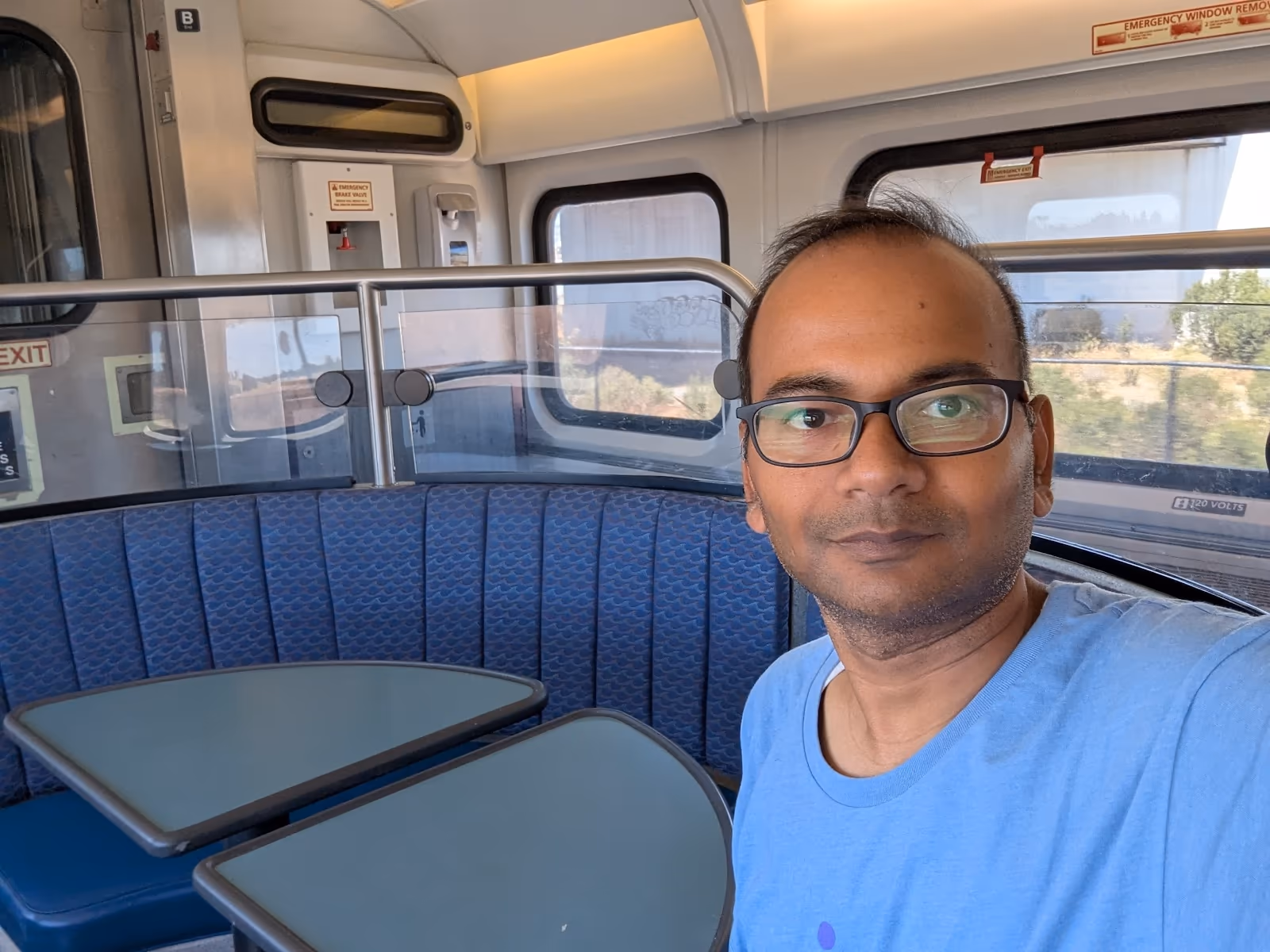 Interior of the Capitol Corridor train — upper deck single-level coach, table seats with windows, clean and comfortable California-style regional rail