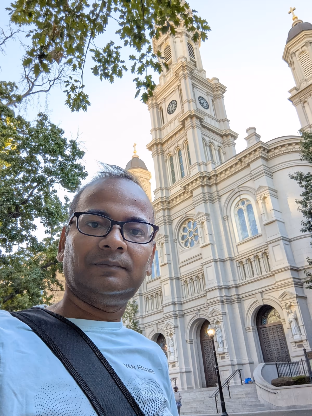 JB in front of the Cathedral of the Blessed Sacrament — grand white neoclassical facade, prominent clock tower, downtown Sacramento