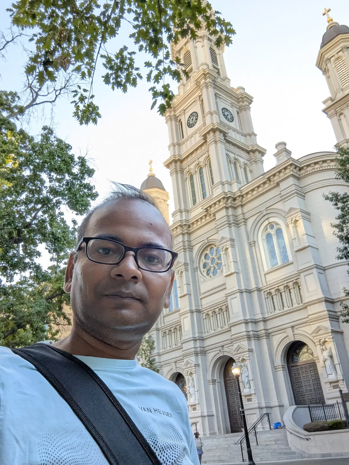 JB in front of the Cathedral of the Blessed Sacrament — grand white neoclassical facade, prominent clock tower, downtown Sacramento