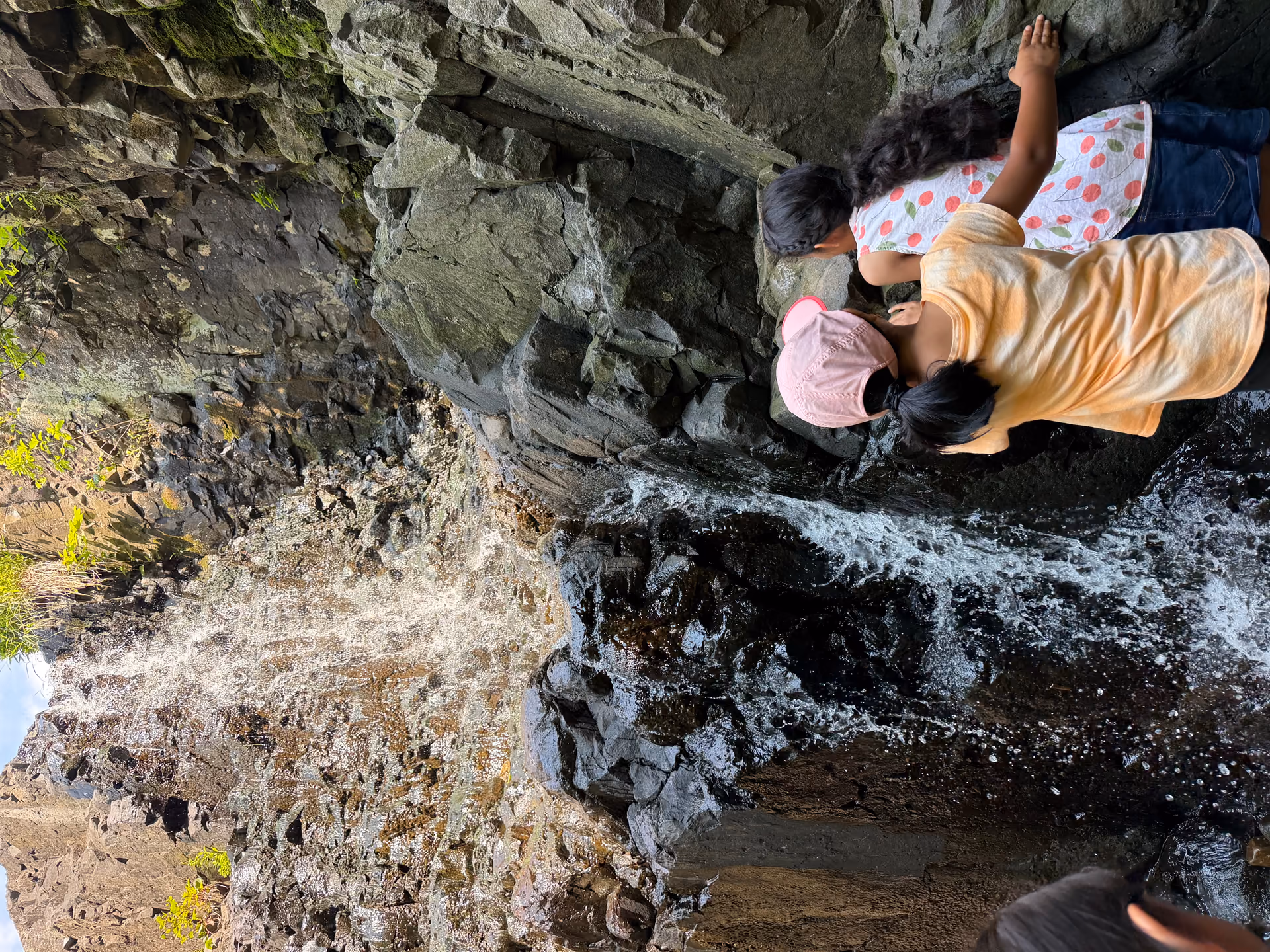 Two young kids playing under the waterfall at Hemlock Falls