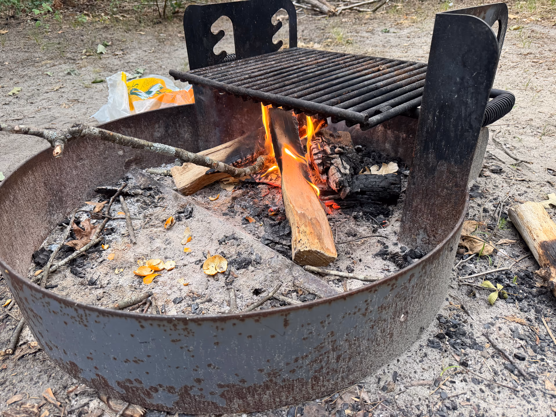 Small evening fire burning under the campsite grill